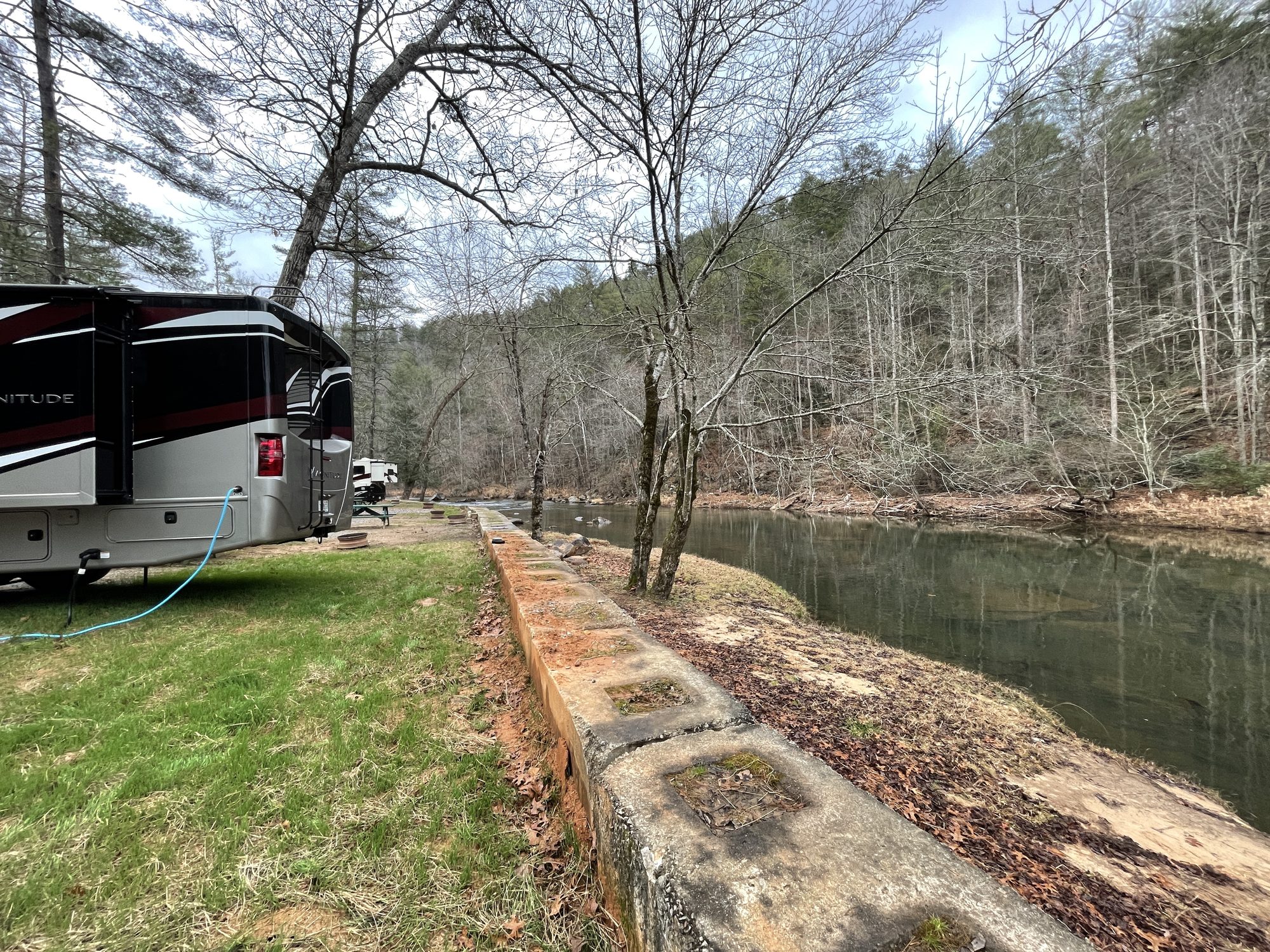 The motorhome parked on the grass beside a mountain river